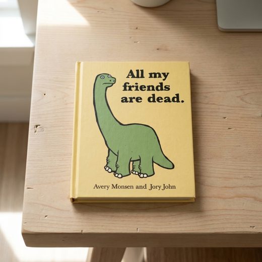 Yellow hardcover book featuring a green dinosaur illustration and the title "All my friends are dead.