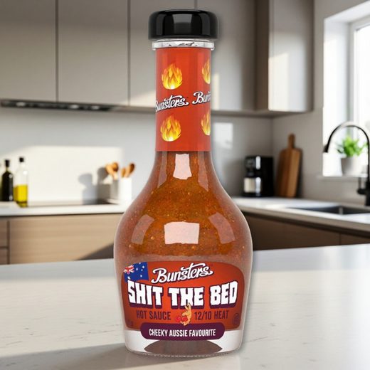 Bunsters Shit The Bed hot sauce bottle filled with fiery orange liquid on a kitchen counter.