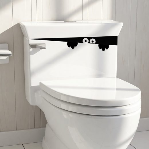Cartoon monster face decal sticker placed on the front of a white toilet tank.