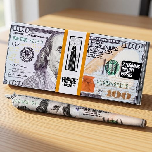 Currency-designed rolling papers featuring the hundred dollar bill, displayed with a rolled sample on wood.
