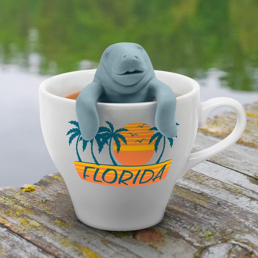 White ceramic mug with Florida palm tree graphic holding a blue manatee tea infuser