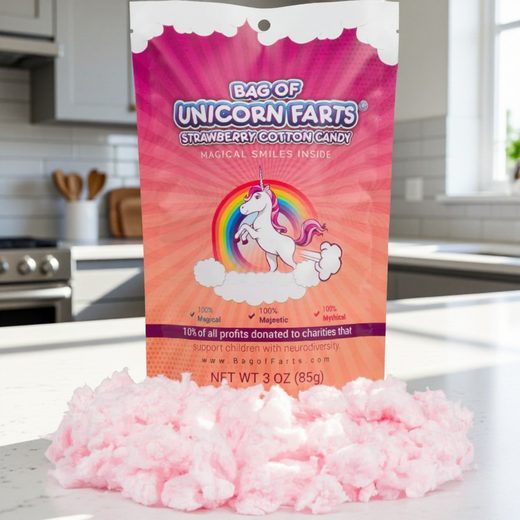 Pink fluffy strawberry cotton candy next to its whimsical unicorn-themed packaging bag.